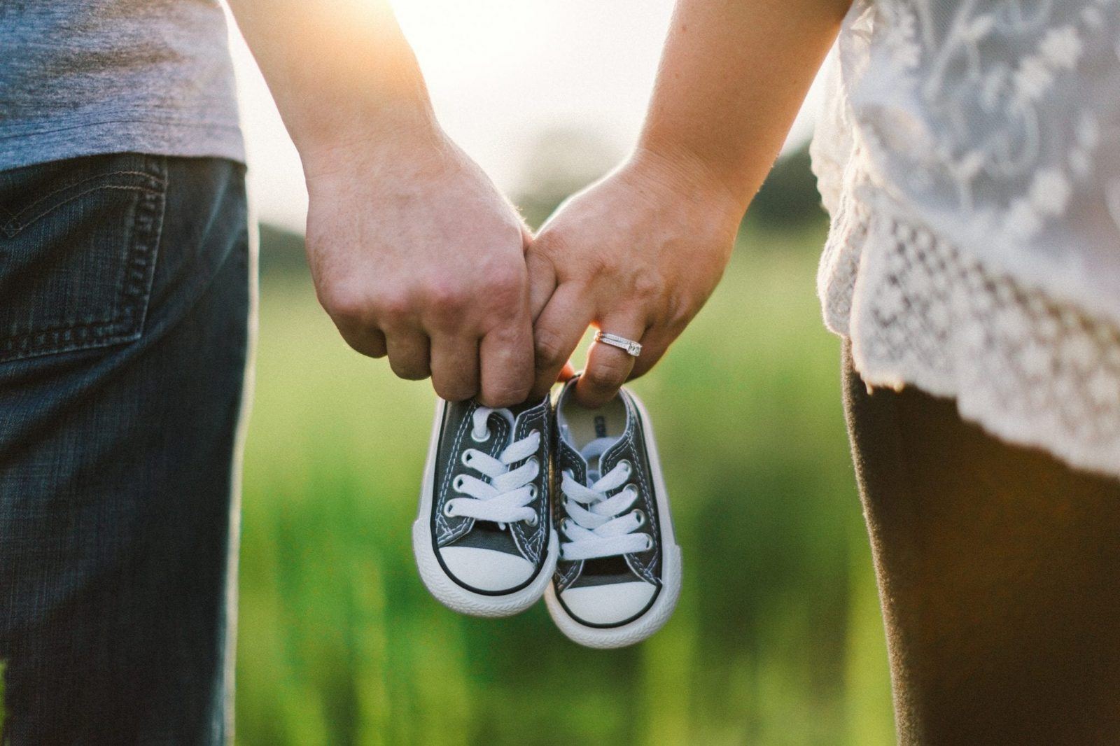 pregnant couple holding baby shoes