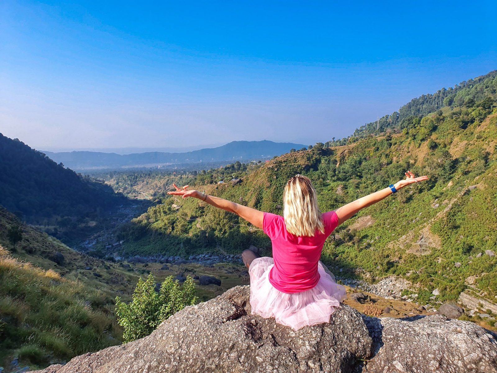 lady sat on top of a mountain with arms stretched out