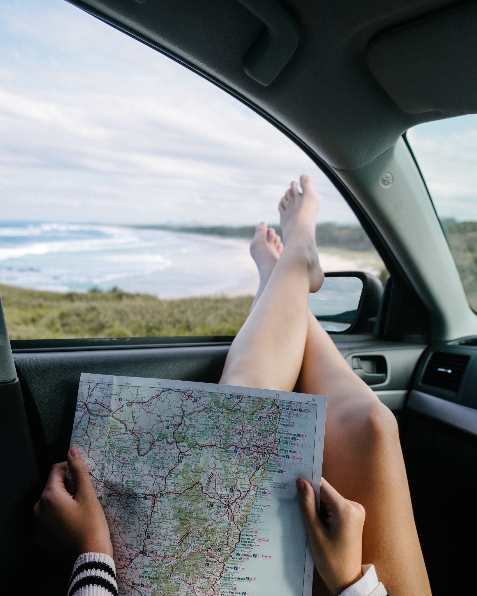 woman holding a map in a car looking out to the sea