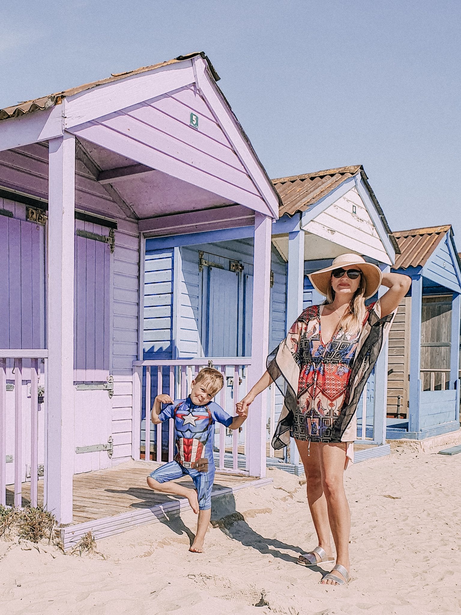 lady and child stood in front of beach huts, best UK holidays
