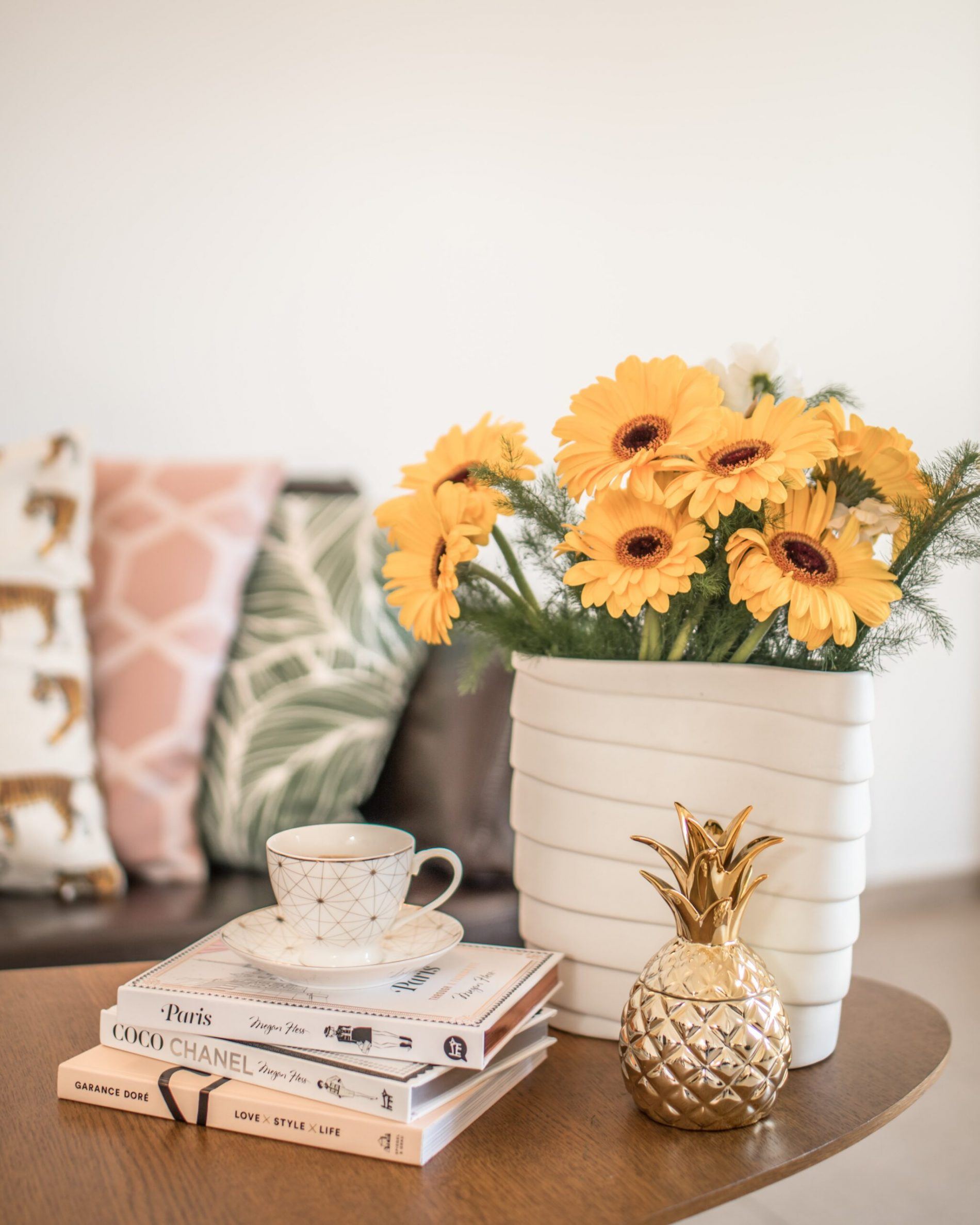 large vase of sunflowers on a table with lots of cushions in background