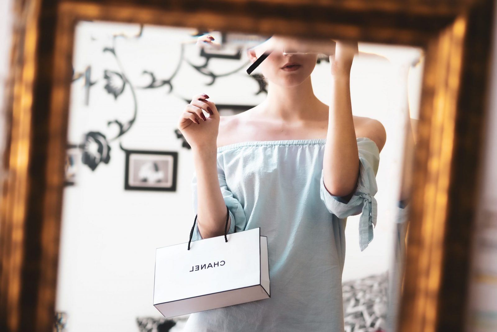 woman holiding luxury shopping bag in the mirror