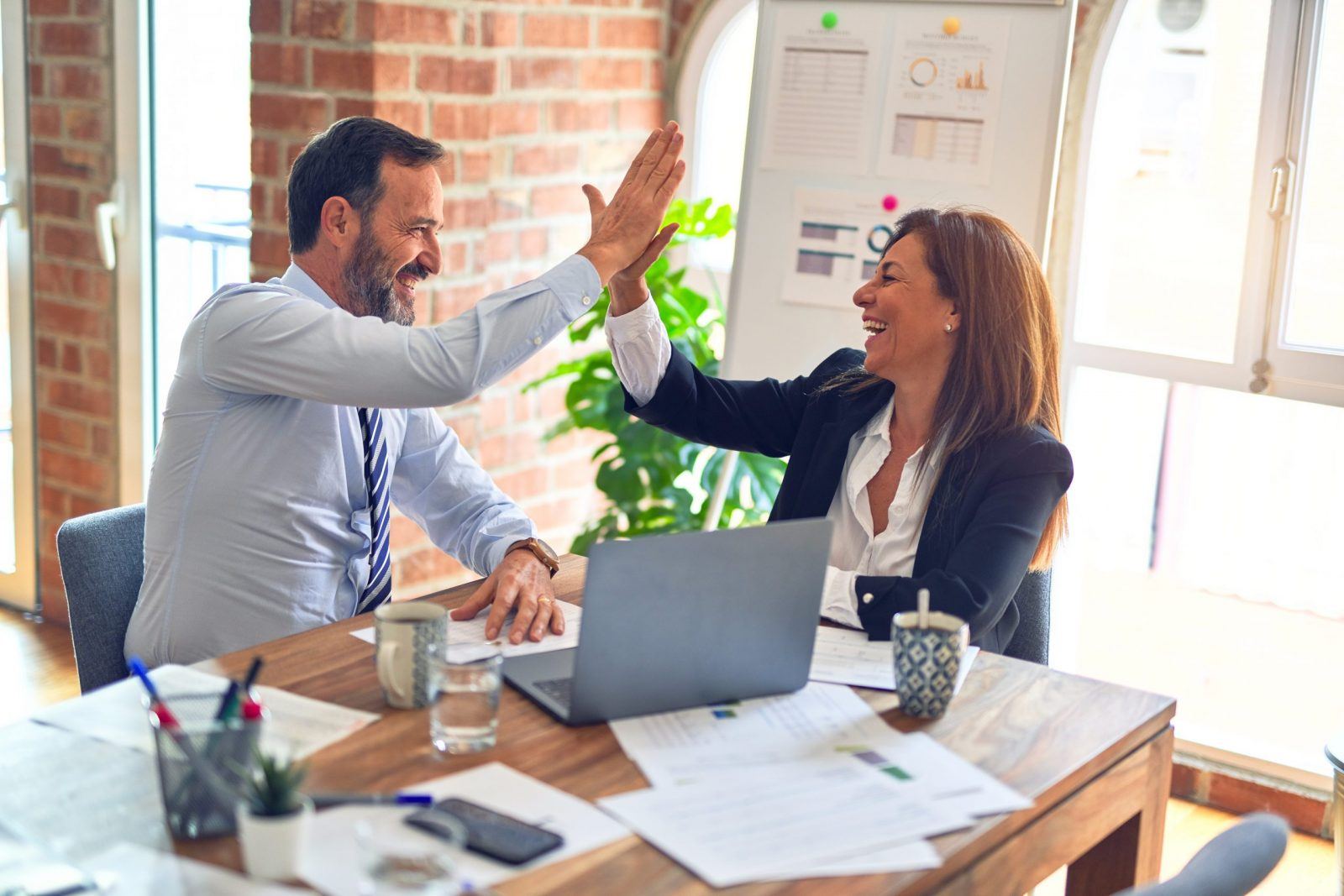 two people high-fiving, representing the FIRE movement and how being frugal and intentional with spending can help with financial freedom