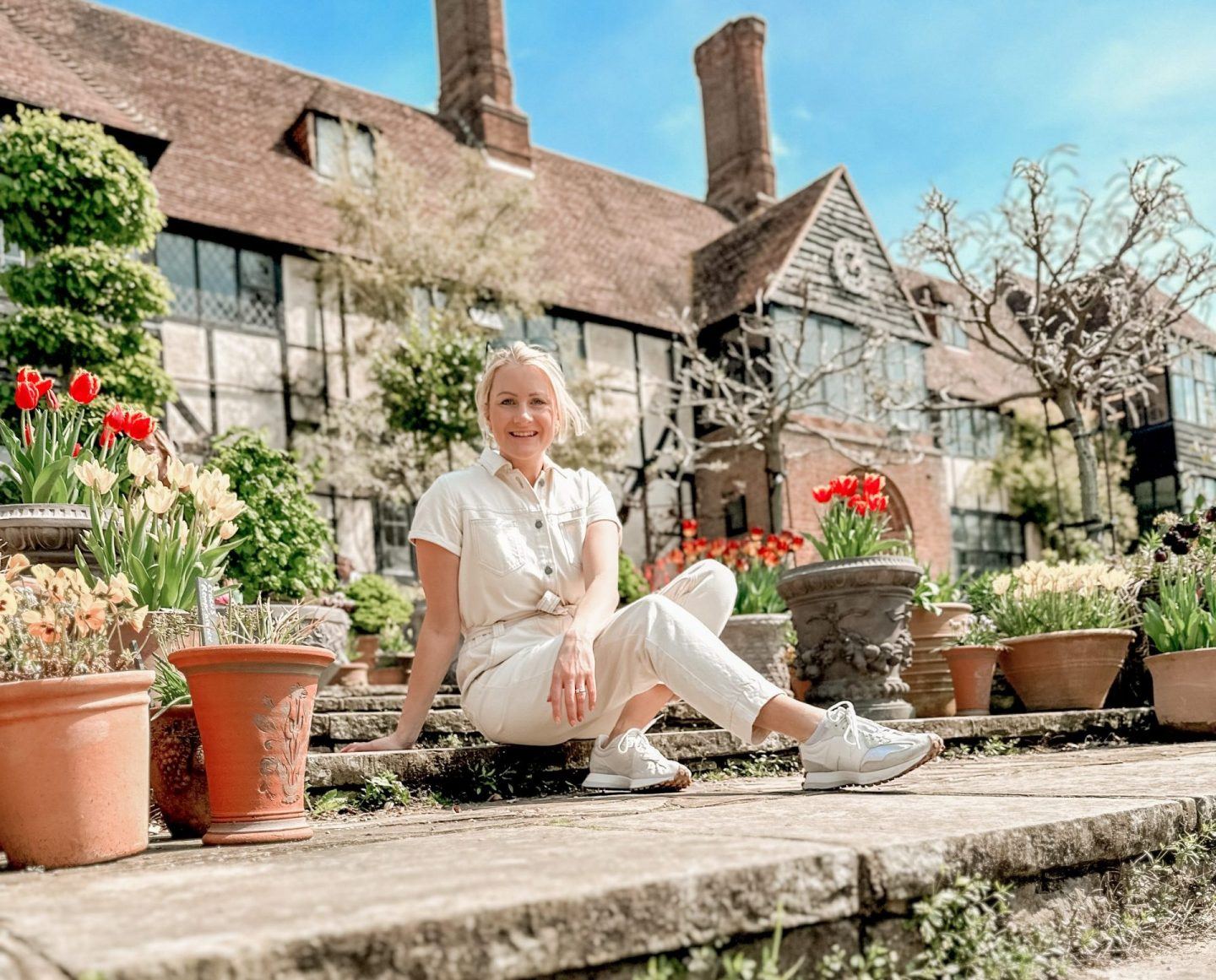 lady sat in front of lovely home to show ways of saving money on travel lady sat on stone steps with flowers around her to represent a emotional feelings of the cost of living crisis