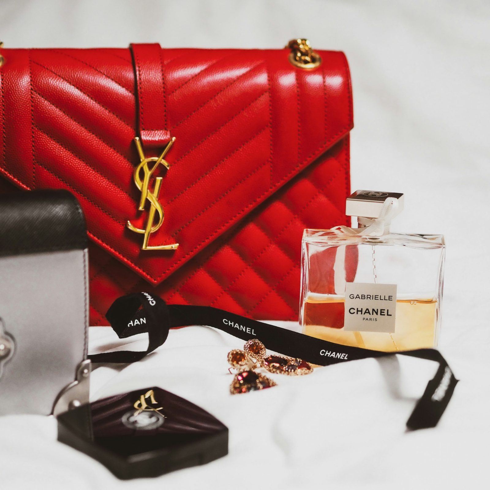 luxury items such as designer handbag, perfume and watch laid out to demonstrate looking at budgeting as a way of affording luxury items